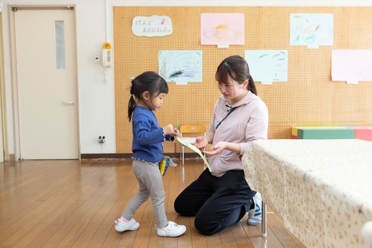 作品を先生に見せる園児